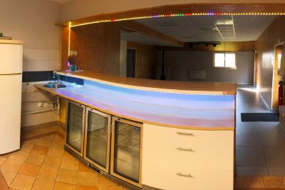 Chaise en bois marquée ’Gîte de la Barre’ dans un jardin verdoyant près d'une maison en pierre et crépi.