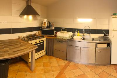 Chaise en bois marquée ’Gîte de la Barre’ dans un jardin verdoyant près d'une maison en pierre et crépi.