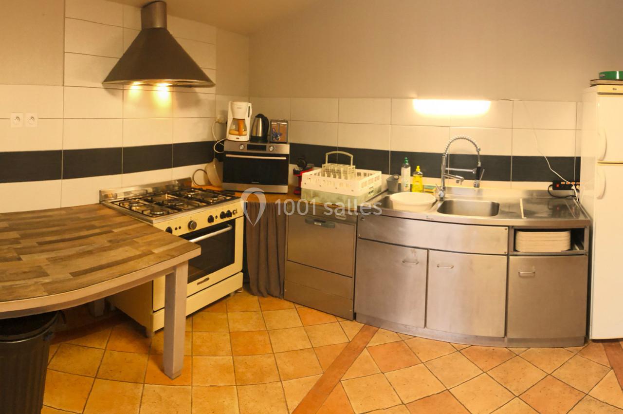 Cuisine équipée avec un plan de travail en bois, un four, une hotte, un évier, un lave-vaisselle et des rangements.