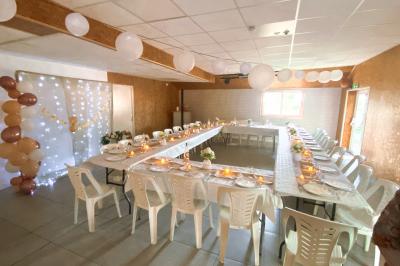 Chaise en bois marquée ’Gîte de la Barre’ dans un jardin verdoyant près d'une maison en pierre et crépi.
