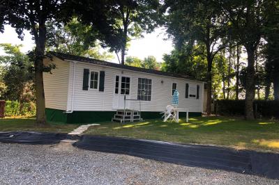 Chaise en bois marquée ’Gîte de la Barre’ dans un jardin verdoyant près d'une maison en pierre et crépi.