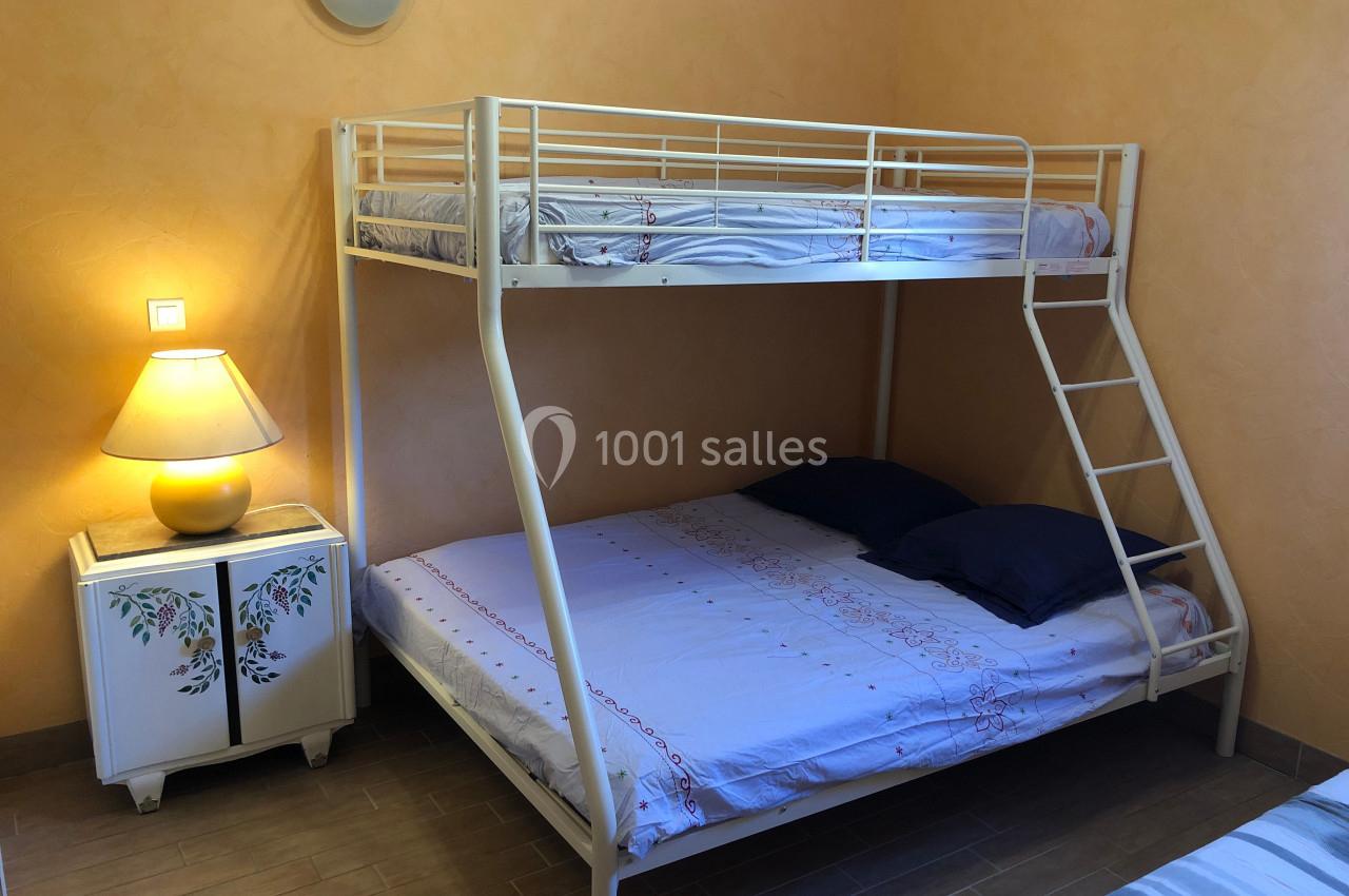 Lit superposé avec un lit double en bas et un lit simple en haut, dans une chambre aux murs orange avec une lampe de chevet.