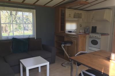 Chaise en bois marquée ’Gîte de la Barre’ dans un jardin verdoyant près d'une maison en pierre et crépi.