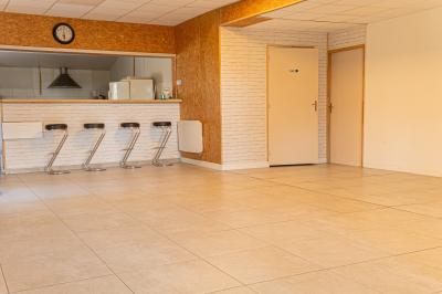 Chaise en bois marquée ’Gîte de la Barre’ dans un jardin verdoyant près d'une maison en pierre et crépi.