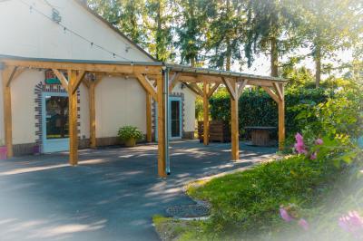 Chaise en bois marquée ’Gîte de la Barre’ dans un jardin verdoyant près d'une maison en pierre et crépi.