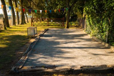 Chaise en bois marquée ’Gîte de la Barre’ dans un jardin verdoyant près d'une maison en pierre et crépi.