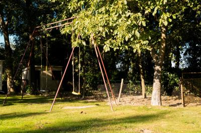 Chaise en bois marquée ’Gîte de la Barre’ dans un jardin verdoyant près d'une maison en pierre et crépi.