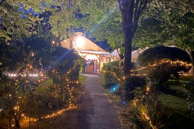 Chaise en bois marquée ’Gîte de la Barre’ dans un jardin verdoyant près d'une maison en pierre et crépi.