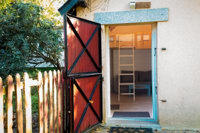 Chaise en bois marquée ’Gîte de la Barre’ dans un jardin verdoyant près d'une maison en pierre et crépi.