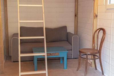 Chaise en bois marquée ’Gîte de la Barre’ dans un jardin verdoyant près d'une maison en pierre et crépi.