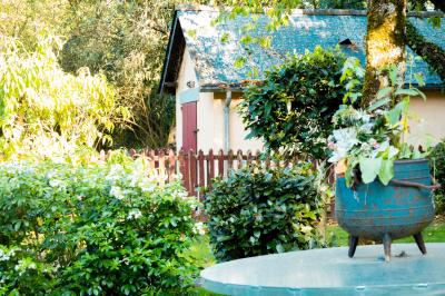 Chaise en bois marquée ’Gîte de la Barre’ dans un jardin verdoyant près d'une maison en pierre et crépi.