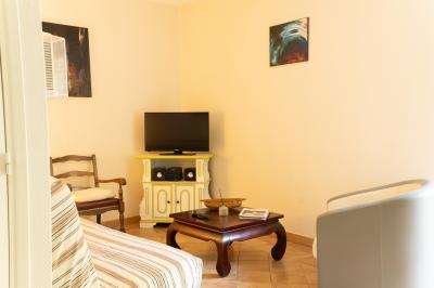 Chaise en bois marquée ’Gîte de la Barre’ dans un jardin verdoyant près d'une maison en pierre et crépi.