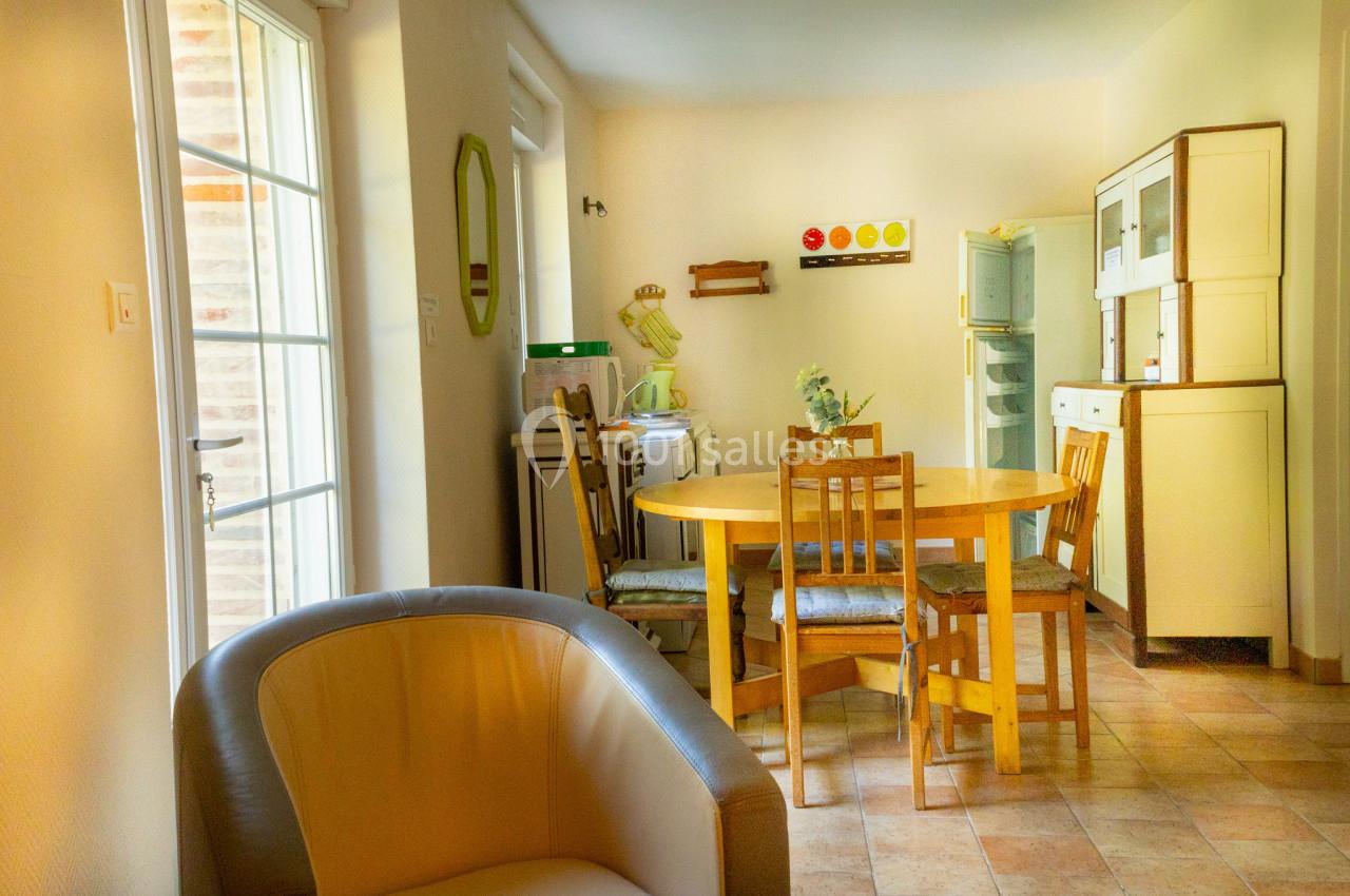 Salle à manger lumineuse avec table ronde en bois, chaises assorties et mobilier rétro dans un intérieur clair.