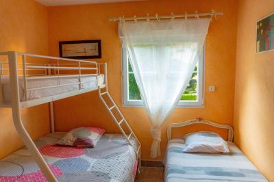 Chaise en bois marquée ’Gîte de la Barre’ dans un jardin verdoyant près d'une maison en pierre et crépi.