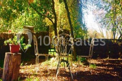 Salle de réception décorée avec des tables dressées, nappes blanches, chaises ajourées et compositions florales.