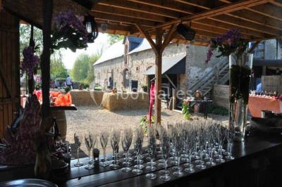 Salle de réception décorée avec des tables dressées, nappes blanches, chaises ajourées et compositions florales.
