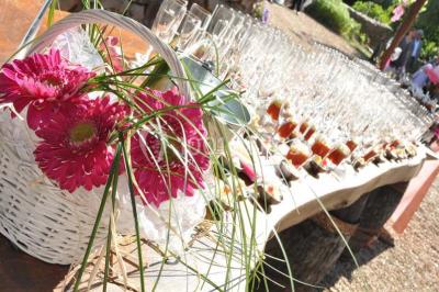 Salle de réception décorée avec des tables dressées, nappes blanches, chaises ajourées et compositions florales.
