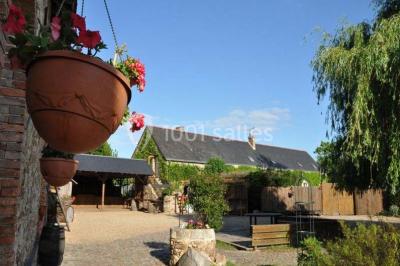 Salle de réception décorée avec des tables dressées, nappes blanches, chaises ajourées et compositions florales.