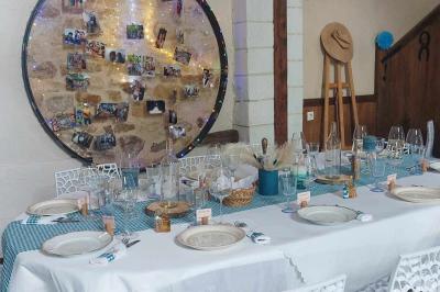 Salle de réception décorée avec des tables dressées, nappes blanches, chaises ajourées et compositions florales.