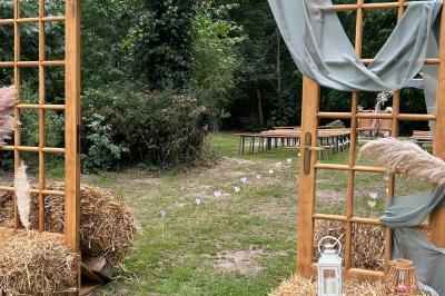 Salle de réception décorée avec des tables dressées, nappes blanches, chaises ajourées et compositions florales.