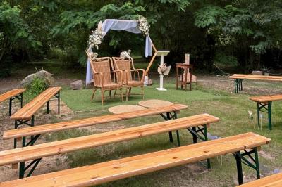 Salle de réception décorée avec des tables dressées, nappes blanches, chaises ajourées et compositions florales.