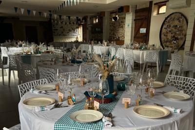 Salle de réception décorée avec des tables dressées, nappes blanches, chaises ajourées et compositions florales.