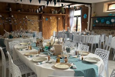 Salle de réception décorée avec des tables dressées, nappes blanches, chaises ajourées et compositions florales.