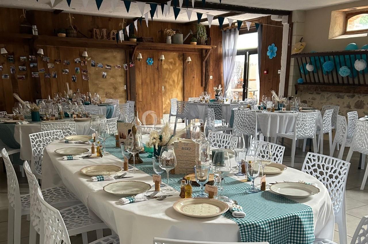Salle décorée pour un événement avec des tables dressées, nappes à carreaux verts et blancs, et guirlandes suspendues.