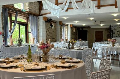 Salle de réception décorée avec des tables dressées, nappes blanches, chaises ajourées et compositions florales.