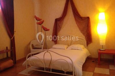 Salle de réception décorée avec des tables dressées, nappes blanches, chaises ajourées et compositions florales.