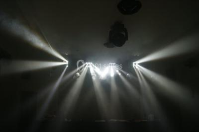 Des projecteurs diffusent des faisceaux lumineux dans une pièce sombre, créant un effet de lumière dramatique.