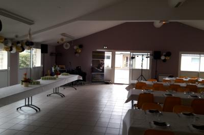 Salle décorée avec table dressée, matériel de sonorisation et panneau promotionnel pour des événements festifs.