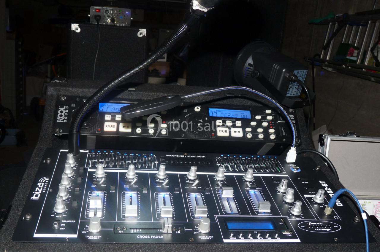 Table de mixage audio avec curseurs, boutons et micros, installée dans un environnement technique.