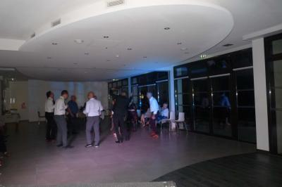 Un groupe de personnes chante au karaoké dans un bar éclairé par des lumières colorées.