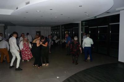 Un groupe de personnes chante au karaoké dans un bar éclairé par des lumières colorées.