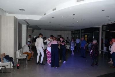 Un groupe de personnes chante au karaoké dans un bar éclairé par des lumières colorées.