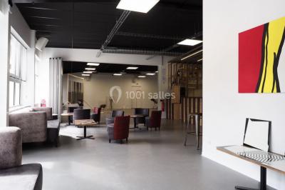 Scène vide éclairée par des projecteurs colorés dans une salle sombre avec un sol en béton.