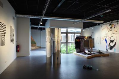 Scène vide éclairée par des projecteurs colorés dans une salle sombre avec un sol en béton.