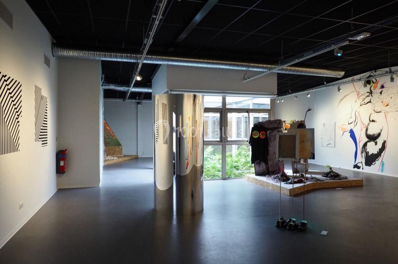 Vue d'une galerie d'art moderne avec des œuvres contemporaines exposées et un éclairage naturel provenant d'une fenêtre.