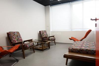 Scène vide éclairée par des projecteurs colorés dans une salle sombre avec un sol en béton.