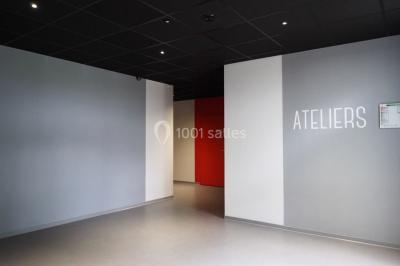Scène vide éclairée par des projecteurs colorés dans une salle sombre avec un sol en béton.