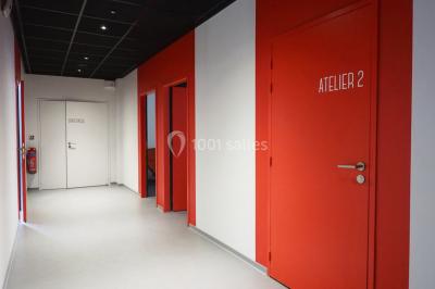 Scène vide éclairée par des projecteurs colorés dans une salle sombre avec un sol en béton.