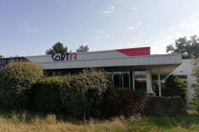 Scène vide éclairée par des projecteurs colorés dans une salle sombre avec un sol en béton.