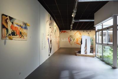 Salle vide avec sol en béton, murs sombres, éclairage au plafond et une table de mixage au fond.