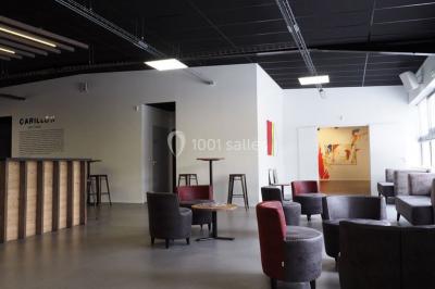 Salle vide avec sol en béton, murs sombres, éclairage au plafond et une table de mixage au fond.
