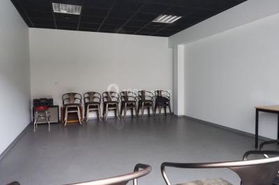 Salle vide avec sol en béton, murs sombres, éclairage au plafond et une table de mixage au fond.