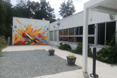 Salle vide avec sol en béton, murs sombres, éclairage au plafond et une table de mixage au fond.