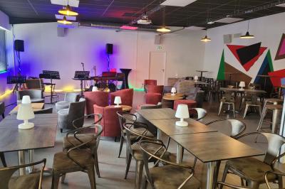 Salle vide avec sol en béton, murs sombres, éclairage au plafond et une table de mixage au fond.