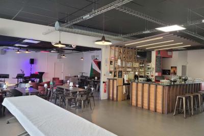 Salle vide avec sol en béton, murs sombres, éclairage au plafond et une table de mixage au fond.