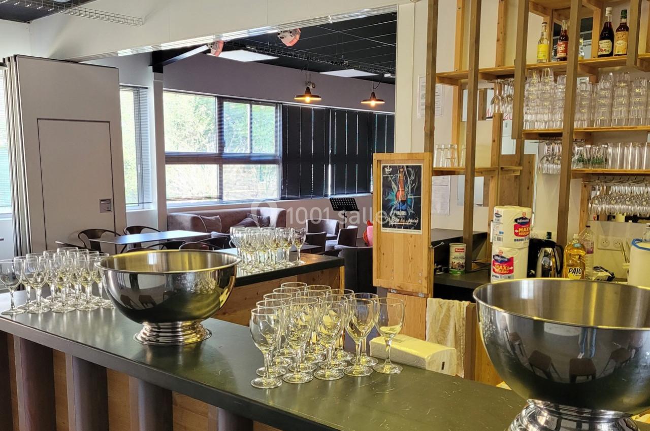 Un bar avec des verres et des seaux à champagne sur un comptoir, dans un espace lumineux avec des canapés en arrière-plan.